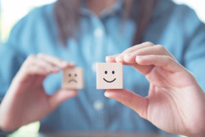 Person holding up blocks with happy and unhappy faces